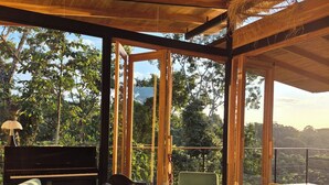 Una habitación amplia con un piano de cola, asientos cómodos y ventanas grandes que ofrecen una vista panorámica.