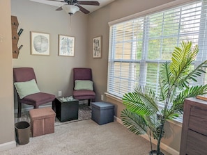 A room with two chairs, a small table, a potted plant, and a window with blinds. - 4BR Home with calif king bed Sleeps 10, Gym near Airport (Atlanta)