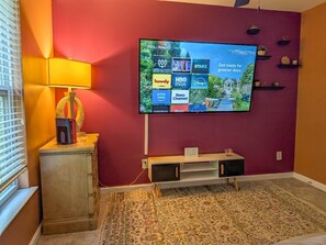 Ein Zimmer mit einem an der Wand befestigten Flachbildfernseher, der verschiedene Streaming-Dienste anzeigt.