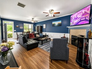 A living room with a black leather sofa, a grey armchair, a coffee table, and a fireplace.