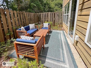 A patio with wooden furniture, a wooden fence, and a house with a window. - 4BR Home with calif king bed Sleeps 10, Gym near Airport (Atlanta)