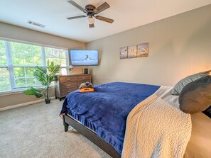 A bedroom with a bed, a television, a ceiling fan, a dresser, and a window with blinds. - 4BR Home with calif king bed Sleeps 10, Gym near Airport (Atlanta)