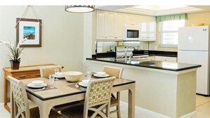 Una cocina moderna con armarios blancos, encimera negra y microondas integrado.