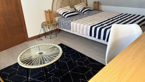 Een slaapkamer met een bed, een stoel, een klein tafeltje en een decoratief wandpaneel.