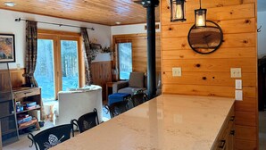 A wooden interior with a central island, black chairs, and a dining table.