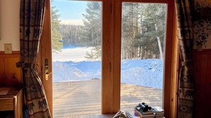 A cozy room with a large window, a wooden ceiling, and a comfortable sofa.