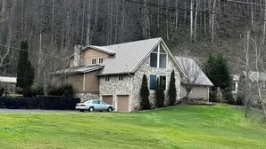 Une maison à deux étages avec une façade en pierre, un toit en pente et un garage.
