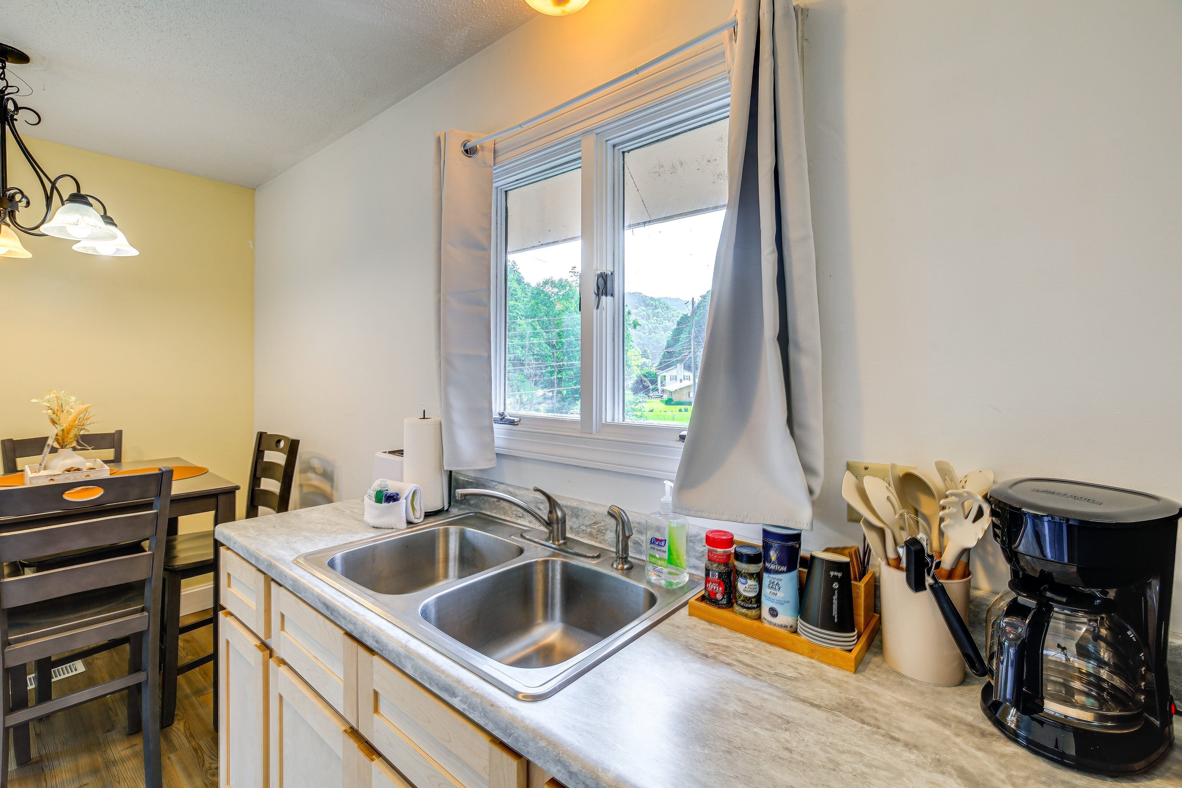 A kitchen with two sinks, a coffee maker, and a window with curtains.