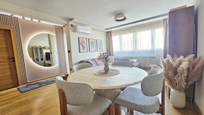 A modern dining area with a round table, six chairs, and a vase with flowers. - Peaceful 1-bedroom apartment in charming Novi Sad (Novi Sad)
