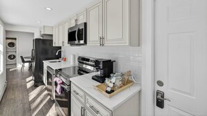 A modern kitchen with white cabinetry, stainless steel appliances, and a central island.