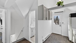Cocina moderna con horno empotrado, refrigerador y ventana con vistas a árboles.
