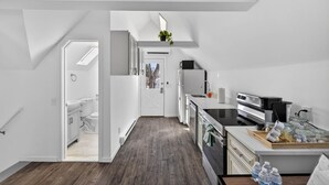 Una cocina moderna con electrodomésticos blancos, piso de madera y vistas al exterior.