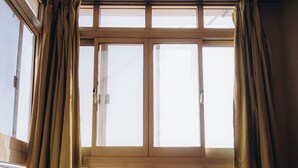 Una habitación con un ventanal grande, una silla de madera y piso de baldosas.