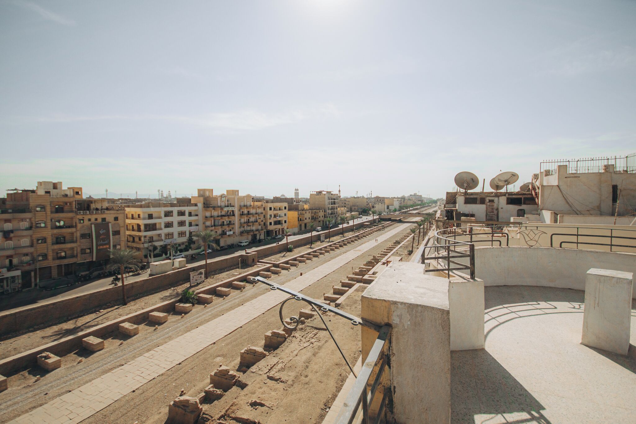 A view of a cityscape with buildings, a road, and satellite dishes.