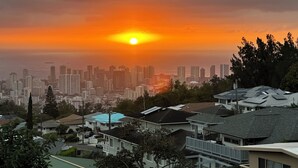 Eine Skyline im Abendrot, mit Wohnhäusern im Vordergrund und freiem Blick auf die Stadt.