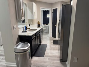 A modern kitchen with a stainless steel refrigerator, a sink, and a trash can. - Spacious 4-bedroom house in gorgeous College Park with AC (College Park)