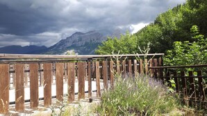 Ein Holzzaun mit Blick auf Berge und einen bewölkten Himmel.