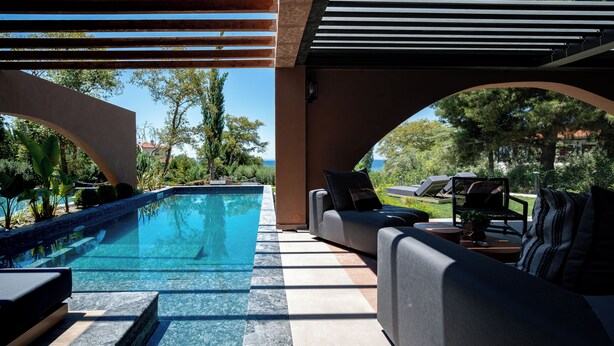 Uma área na piscina com espaço de estar integrado, pérgola e vista para a paisagem ao redor.