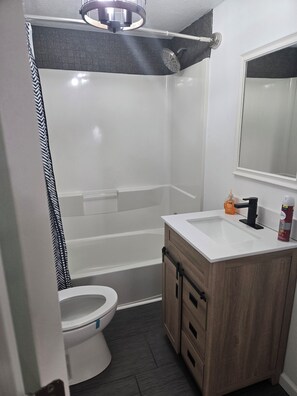 Casa de banho moderna com chuveiro, sanita e lavatório.