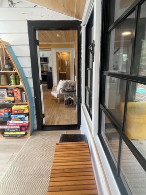 A hotel lobby with a wooden bench, a game shelf, and a view into the dining area.