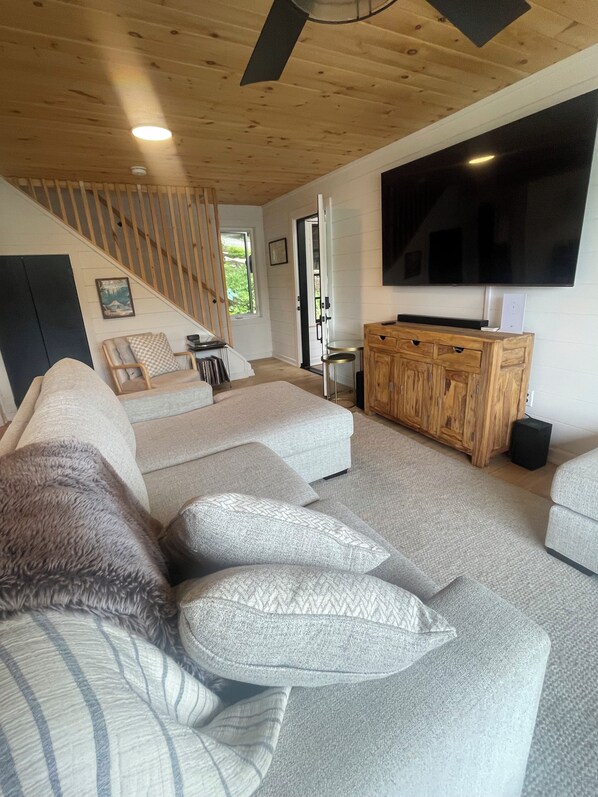 Ein modernes Wohnzimmer mit einer Couch, einem Fernseher und einem Holzschrank.