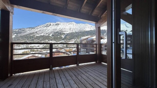 A wooden balcony with a view of snow-covered mountains and buildings. - 150m from ski slopes, 3rd floor, view ski slopes, balcony, tv, ski locker, 100m², Valmorel (Valmorel)