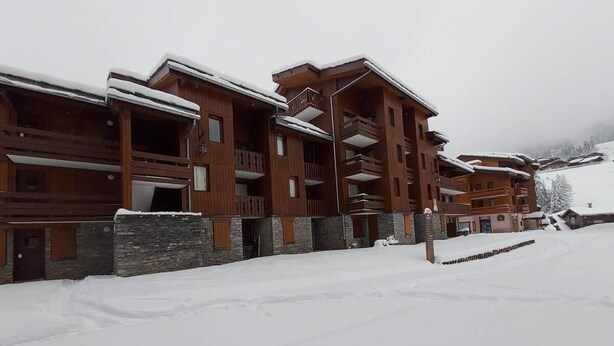 A snow-covered building with multiple balconies and a stone foundation. - Ski-in/ski-out & foot of the slopes, Ground floor, view ski slopes, terrace, tv, ski locker, 27m² (Valmorel)