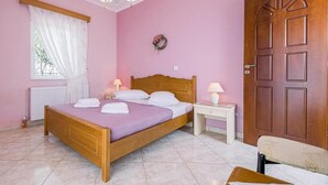 A bedroom with a wooden bed, a nightstand, a desk, a chair, and a door.