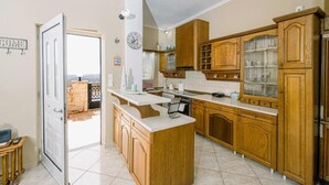 A kitchen with wooden cabinets, a central island, and a view through an open door.