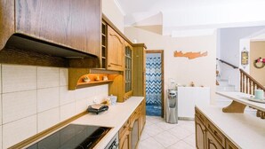 A kitchen with wooden cabinets, a built-in stove, and a countertop with a kettle and a coffee maker.