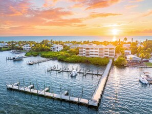 A waterfront property with a dock, boats, and a row of houses. - Peaceful Bayfront Escape in Captiva Island Village- Stunning water views (Captiva)