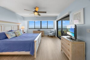 Ein Schlafzimmer mit Bett, Fernseher, Sessel, Kommode und Meerblick.