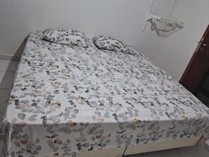 A bed with a floral bedspread and two pillows. - Marvelous 3-bedroom apartment in Rio de Janeiro near the National Park (Rio de Janeiro)
