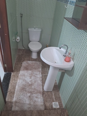 A bathroom with a toilet, sink, and a shower area. - Marvelous 3-bedroom apartment in Rio de Janeiro near the National Park (Rio de Janeiro)