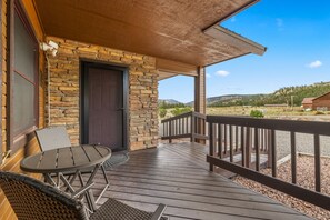 Une terrasse en bois avec un mur en pierre, une porte et une vue sur le paysage environnant.
