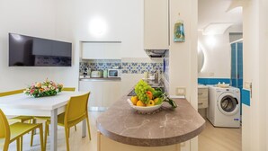 Una cocina moderna con comedor, lavadora y televisor de pantalla plana.