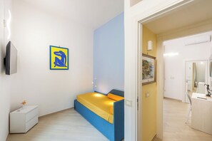 A compact bedroom with a bed, bedside table, and a wall-mounted TV.