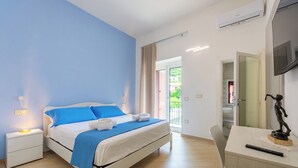 Un dormitorio con cama, mesitas de noche, escritorio y televisor.