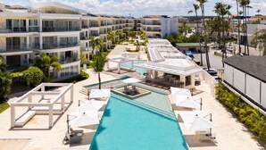 Ett semesterhotell med en central pool, flera balkonger och palmer.