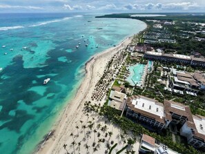 An aerial view of a coastal resort with a beach, swimming pools, and hotel buildings. - Luxury Suite, 2 Bedrooms, Partial Ocean View (Punta Cana)