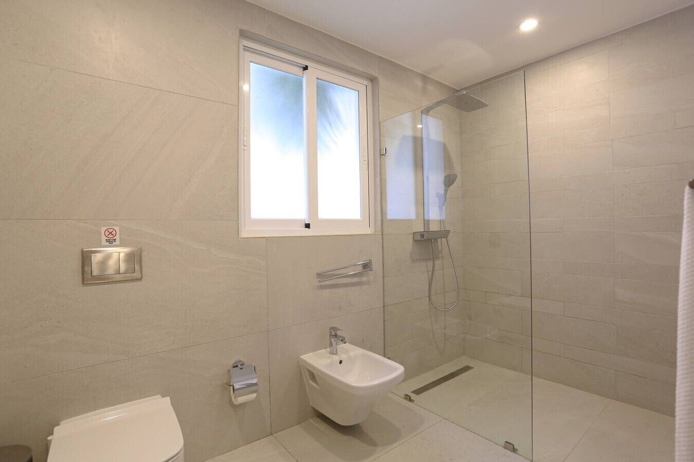 Een moderne badkamer met een douchecabine van glas, een bidet en een toilet.