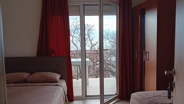A bedroom with a bed, a wardrobe, and a sliding glass door leading to an outdoor area. - Classic Studio Apartment with Sea View and Terrace (Sutomore)