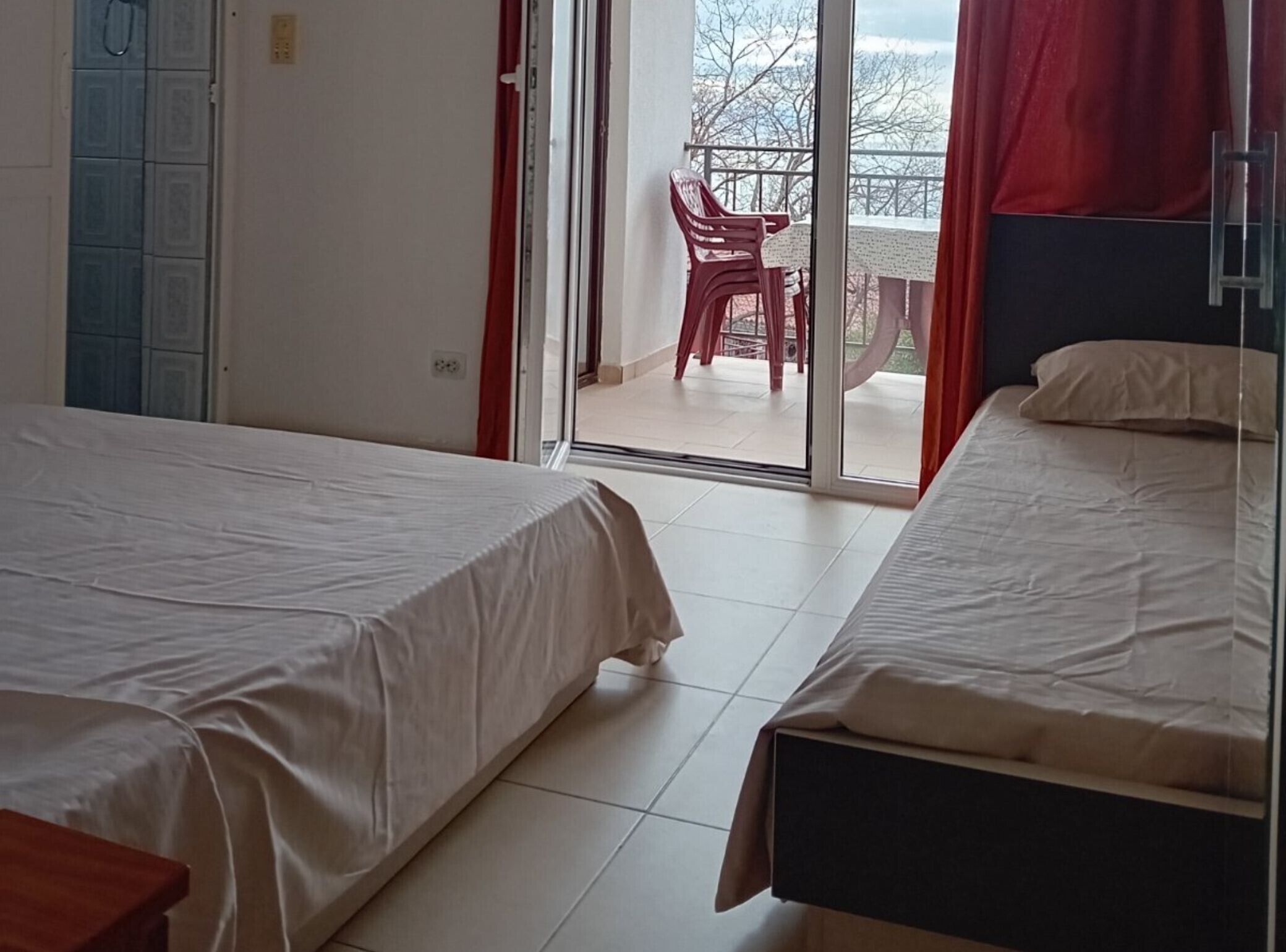 Une chambre d’hôtel avec deux lits, une porte-fenêtre coulissante donnant sur un balcon et une vue sur l’extérieur.