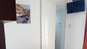 A bedroom with a bed, a door, a wall-mounted TV, and a window. - Comfort Studio Apartment with Sea View and Terrace (Sutomore)