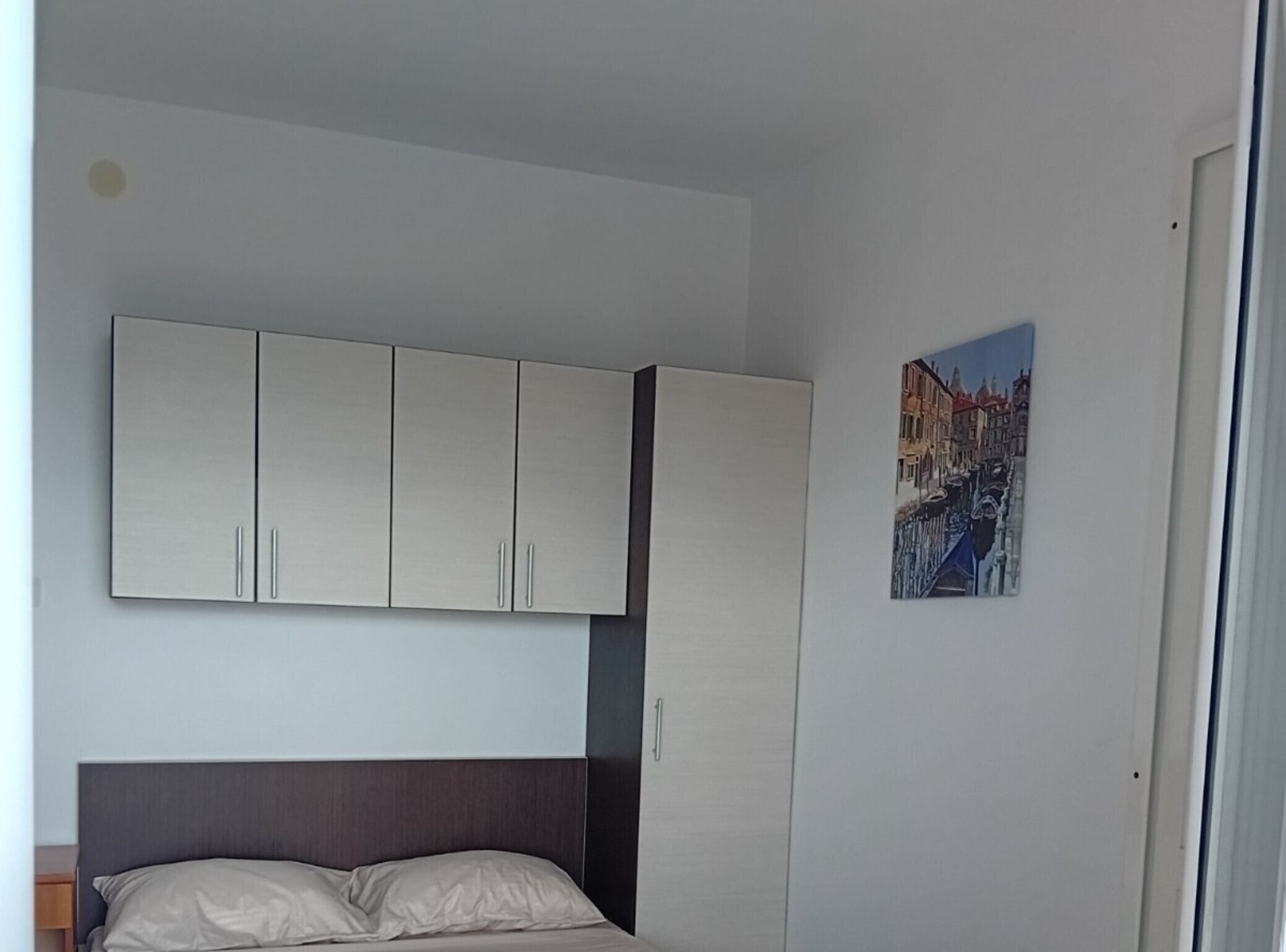 Un dormitorio con cama, armario y un cuadro en la pared.
