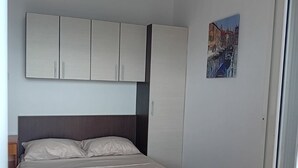 A bedroom with a bed, a wardrobe, and a wall-mounted picture. - Comfort Studio Apartment with Sea View and Terrace (Sutomore)