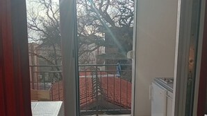 A balcony with a view of a red-roofed building and bare trees. - Superior Studio Apartment with Sea View and Terrace (Sutomore)