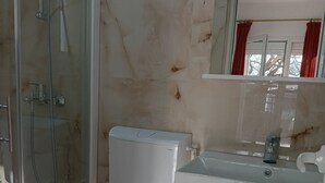 A bathroom with a glass shower enclosure, a white toilet, and a sink with a mirror above it. - Superior Studio Apartment with Sea View and Terrace (Sutomore)