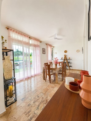 Un espace repas comprenant une table et des chaises, un ventilateur de plafond et une vue dégagée grâce à de grandes fenêtres.