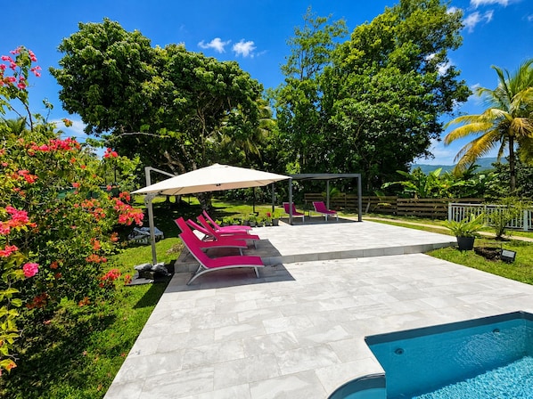 Un espace aménagé au bord de la piscine, avec des chaises longues et un coin salon abrité.